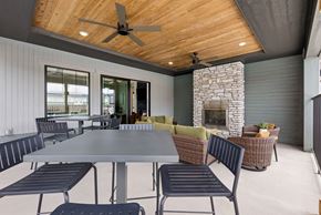 Denver townhouse for rent - A modern outdoor dining area with a stone fireplace and a ceiling fan.