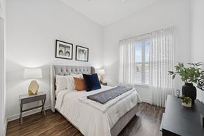 Farmers Branch apartment for rent - A bedroom with a large bed and a window with white curtains.