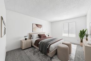 Dallas apartment for rent - A bedroom with a large bed and a small table with a plant on it.