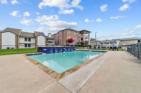Dallas apartment for rent - A swimming pool surrounded by a concrete floor and a fence.