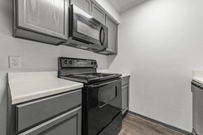 Dallas apartment for rent - A black stove top oven sits in a kitchen with a white counter top.