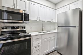Austin apartment for rent - A modern kitchen with white cabinets and stainless steel appliances.
