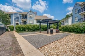 Austin apartment for rent - A sunny day at a residential area with apartment buildings and a gravel area with a gazebo.