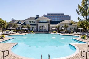 Atlanta apartment for rent - A large swimming pool in front of a building with a blue sky in the background.