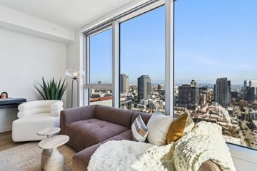 San Diego apartment for rent - A living room with a brown couch and a large window overlooking a cityscape.