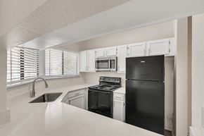 Dallas apartment for rent - an empty kitchen with black appliances and white cabinets
