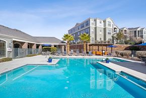 El Paso apartment for rent - A large swimming pool in front of a building with a fence around it.
