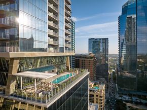 Austin apartment for rent - A modern building with a pool on the roof overlooks a busy street.