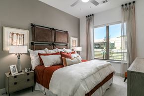 Dallas apartment for rent - A bedroom with a large bed and a window overlooking a building.
