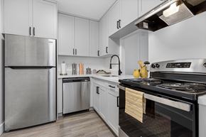 North Miami Beach apartment for rent - A modern kitchen with a stainless steel refrigerator and a stove with a pot on it.
