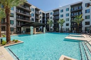 Gilbert apartment for rent - A large swimming pool in front of a multi-story apartment building.