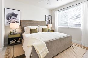 Phoenix apartment for rent - A bedroom with a large bed and a picture of a man on the wall.