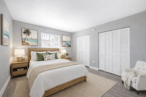 Fort Myers apartment for rent - A bedroom with a large bed, a nightstand with lamps, a chair, and pictures on the wall.