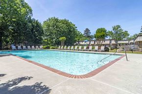 Forest Park apartment for rent - A large outdoor swimming pool surrounded by trees and a fence.