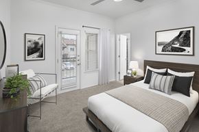 Irving apartment for rent - A bedroom with a large bed and a chair with a potted plant on a table.