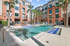 Houston apartment for rent - a swimming pool with blue lounge chairs in front of an apartment building