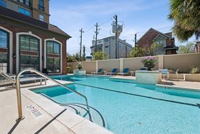 Houston apartment for rent - A swimming pool with a diving board and lounge chairs.