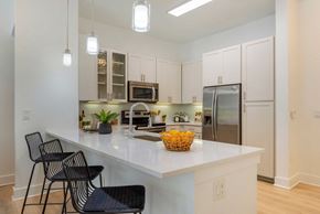 Charlotte apartment for rent - A kitchen with white cabinets and a white countertop with a basket of fruit on it.
