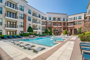 Charlotte apartment for rent - A large swimming pool surrounded by lounge chairs and apartment buildings.