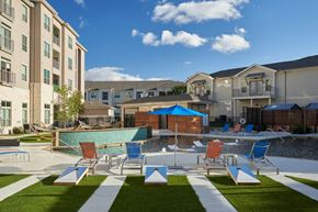 Cedar Park apartment for rent - A sunny day at the poolside with chairs and umbrellas.