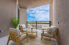 Dallas apartment for rent - A balcony with two chairs and a table with a view of the sky and buildings.
