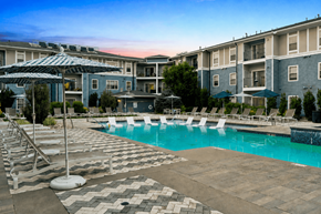Lone Tree apartment for rent - A swimming pool surrounded by lounge chairs and umbrellas in front of apartment buildings.