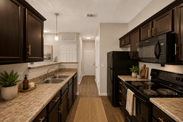 Antioch apartment for rent - A kitchen with dark brown cabinets and a white door in the background.
