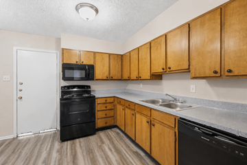 Stephenville apartment for rent - A kitchen with wooden cabinets and black appliances.