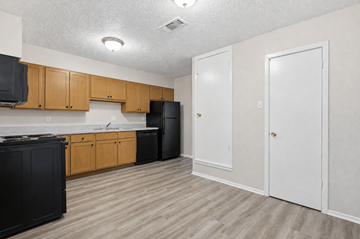 Stephenville apartment for rent - A kitchen with black appliances and wooden cabinets.