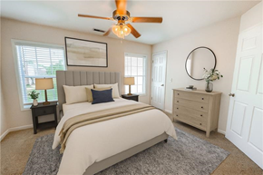 Spring Hill townhouse for rent - A bedroom with a large bed, a ceiling fan, and a nightstand with a lamp.