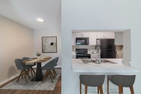 Houston apartment for rent - A kitchen with a table and chairs in the foreground and a microwave, oven, and sink in the background.