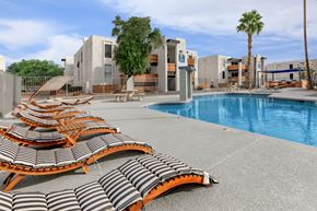 Phoenix apartment for rent - a pool with lounge chairs and palm trees in the background
