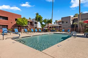 Glendale apartment for rent - a swimming pool with blue lounge chairs and buildings in the background