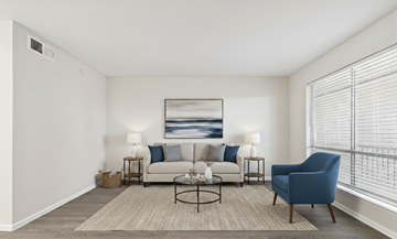 Austin apartment for rent - A living room with a white couch, a blue chair, and a painting on the wall.