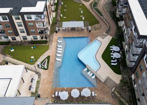 Garland apartment for rent - A large swimming pool surrounded by a grassy area and a concrete walkway.