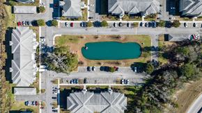 Savannah apartment for rent - A bird's eye view of a parking lot with cars and a pond.