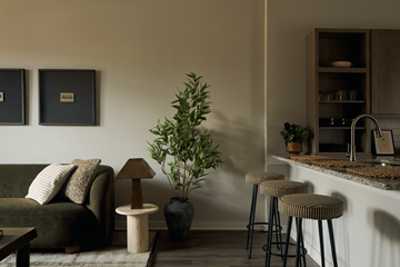 Nashville apartment for rent - A living room with a green couch, a table with a lamp, and a bar area with stools.