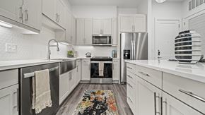 Austin apartment for rent - A modern kitchen with white cabinets and a black refrigerator.