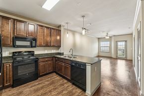 New Braunfels apartment for rent - A kitchen with dark wood cabinets and black appliances.