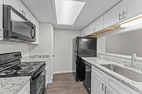 San Antonio townhouse for rent - A black refrigerator stands in a kitchen with granite countertops and stainless steel appliances.