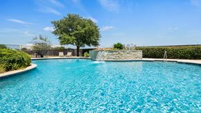 New Braunfels apartment for rent - A pool with a waterfall and a tree in the background.