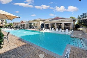 Carrollton apartment for rent - A large outdoor swimming pool with a sun lounger and a building in the background.