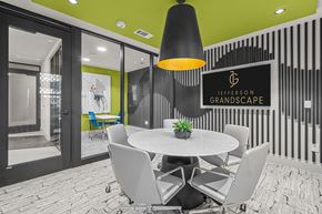 The Colony apartment for rent - A modern dining area with a white table and chairs, a black pendant light, and a sign that reads