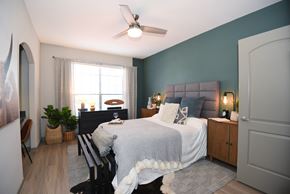Richmond apartment for rent - A bedroom with a bed, a chair, a ceiling fan, and a window.