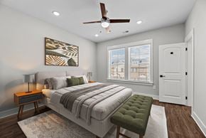 Gallatin townhouse for rent - A bedroom with a large bed, a green ottoman, and a ceiling fan.