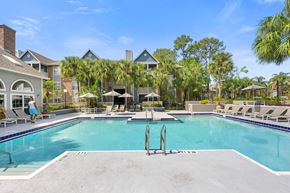 Orlando apartment for rent - a large swimming pool with lounge chairs and umbrellas in front of a building