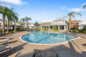 Kissimmee apartment for rent - a swimming pool with palm trees in front of a building