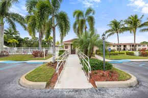 Port Saint Lucie apartment for rent - A building is surrounded by palm trees and a small garden.