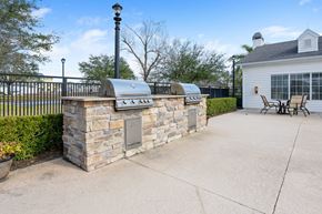 Ormond Beach apartment for rent - a stone outdoor kitchen with a grill and a table and chairs