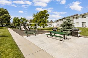 Aurora apartment for rent - A playground with a slide, swings, and a picnic table in a park.